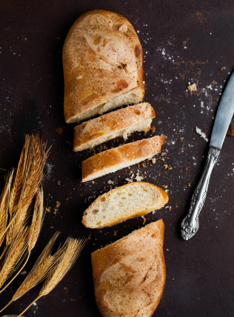 cut bread, ears and a knife on the table.